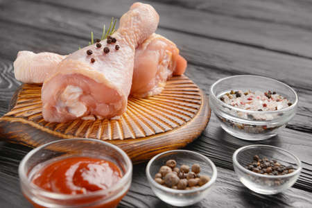 Raw chicken drumsticks and spices on wooden backgroundの写真素材