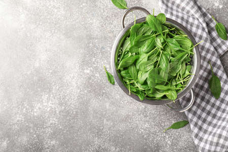 Colander with fresh spinach on table