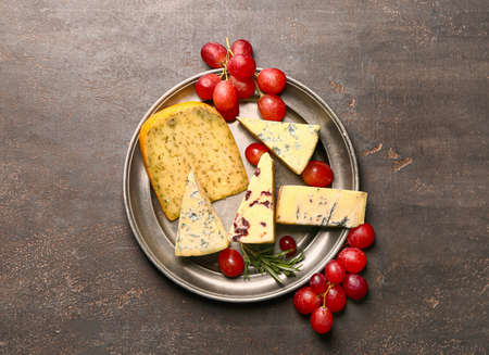 Tray with assortment of fresh cheese on dark background
