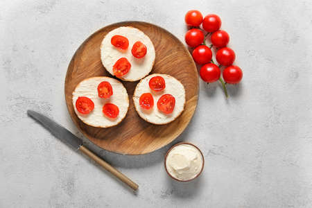 Fresh buns with tasty cream cheese and tomato on white backgroundの写真素材