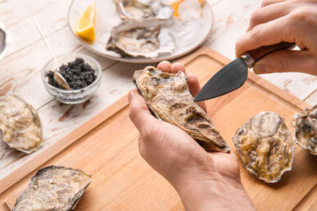 Woman eating tasty oysters at wooden table, closeupの写真素材