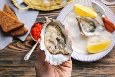 Woman eating tasty oysters at table, closeupの写真素材