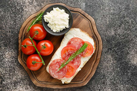 Sandwich with tasty cream cheese, sausages and tomatoes on dark backgroundの写真素材