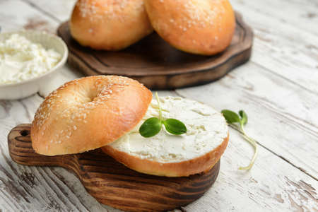 Fresh bun with tasty cream cheese on white wooden backgroundの写真素材