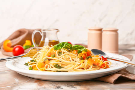 Plate with tasty pasta and vegetables on tableの写真素材