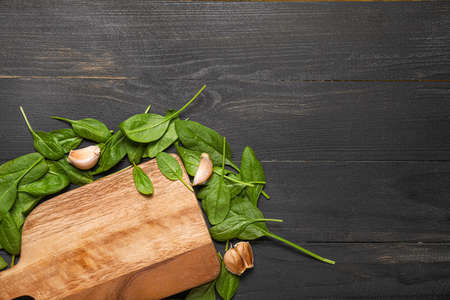 Board with fresh spinach and garlic on dark backgroundの写真素材