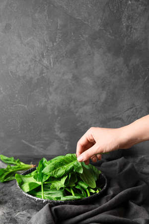 Woman with plate of fresh green spinach at tableの写真素材