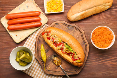 Tasty hot dog and ingredients on wooden backgroundの写真素材