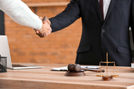 Man and lawyer shaking hands in officeの写真素材