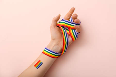 Female hand with rainbow ribbon on color background. LGBT conceptの写真素材