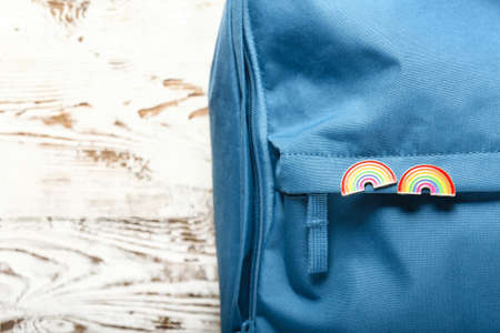 Backpack with pinned rainbow badges as a symbol of LGBT on white wooden backgroundの写真素材