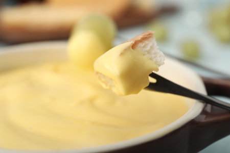 Dipping of crouton into cheese fondue, closeupの写真素材