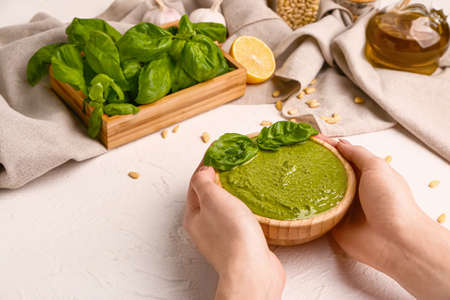 Female hands with pesto sauce in bowl on white backgroundの写真素材