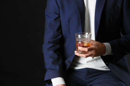 Man in stylish blue clothes and with alcohol on dark backgroundの写真素材