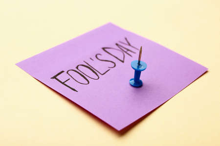 Paper sheet with text FOOL'S DAY on color background
