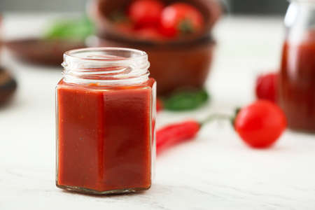 Jar of tomato sauce on white table