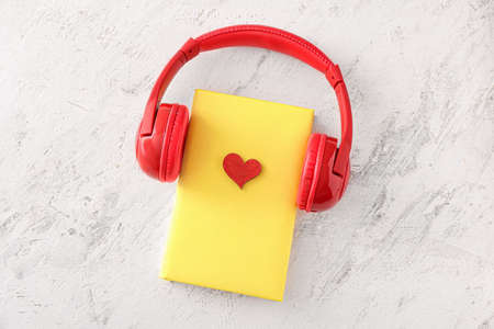 Book and modern headphones on light background. Concept of audiobookの写真素材