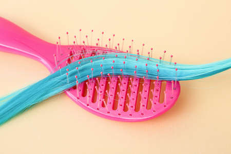Blue hair strand and brush on color background