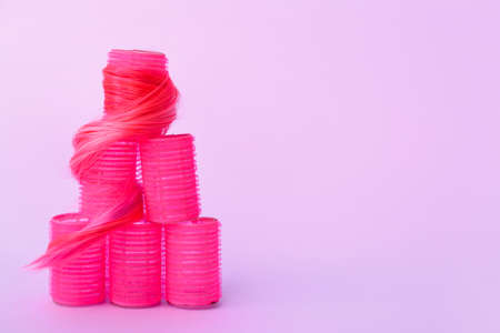 Pink hair curlers with strand on color backgroundの写真素材