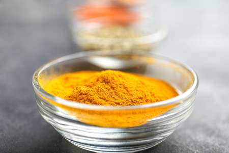 Bowl with tumeric on gray background, closeup