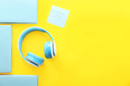 Books and modern headphones on color background. Concept of audiobookの写真素材