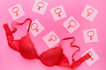 Female bra with symbols of woman on color background. Concept of feminism