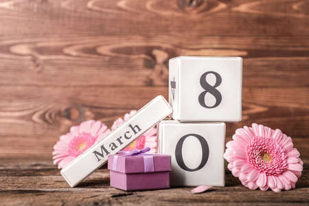 Calendar with date of International Women's Day, gift and flowers on wooden backgroundの写真素材