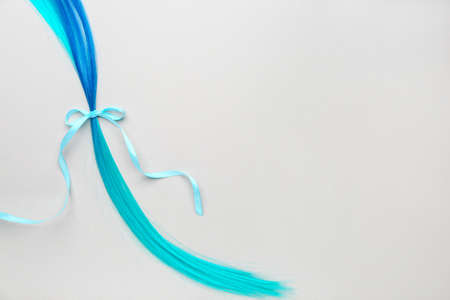 Blue hair strand and ribbon on light background