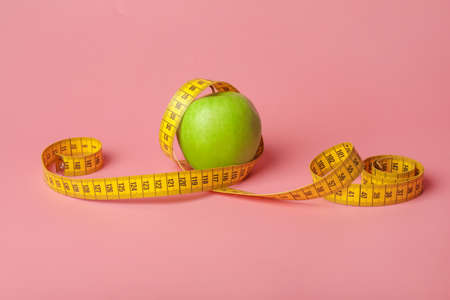 Apple and measuring tape on color background. Diet conceptの写真素材