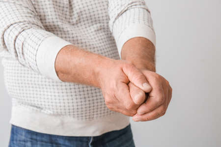 Senior man suffering from Parkinson syndrome on gray background, closeupの写真素材