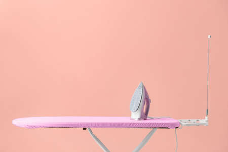 Electric iron and board near color wallの写真素材