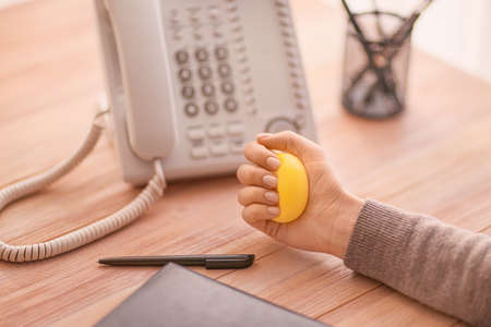Woman squeezing stress ball while working in officeの写真素材