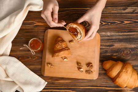 Woman filling croissant with jam, top viewの写真素材