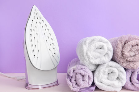 Electric iron and towels on color backgroundの写真素材