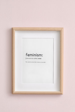 Paper sheet with definition of word FEMINISM in frame on color backgroundの写真素材