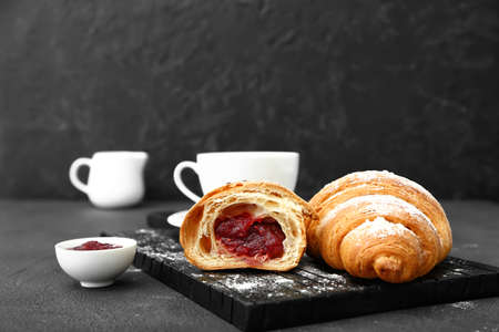 Board with tasty sweet croissants and jam on dark backgroundの写真素材