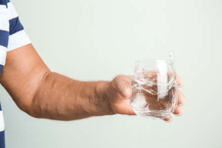 Senior man with Parkinson syndrome holding glass of water on gray backgroundの写真素材