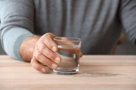 Senior man with Parkinson syndrome drinking water at home, closeupの写真素材