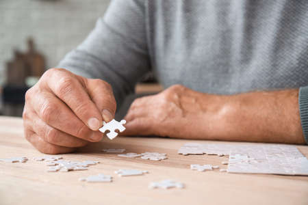 Senior man with Parkinson syndrome doing puzzle at home, closeupの写真素材