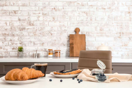 Tasty sweet croissants with jam and coffee on table in kitchenの写真素材