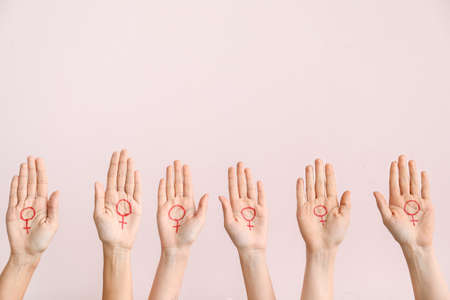Women with drawn symbols of woman on their palms against color background. Concept of feminismの写真素材