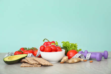 Different healthy food with measuring tape and dumbbells on table. Diet concept