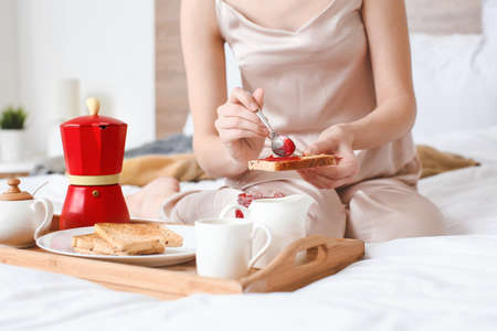 Morning of beautiful young woman having breakfast in bedの写真素材