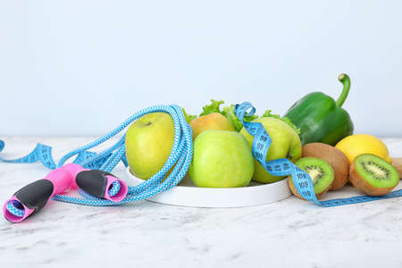 Different healthy food with measuring tape and jumping rope on table. Diet conceptの写真素材