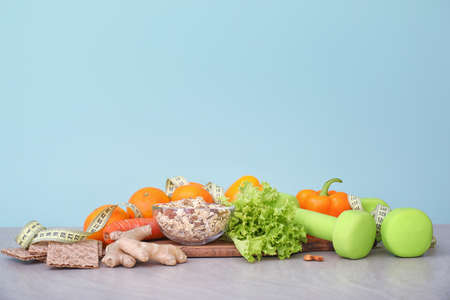 Different healthy food with measuring tape and dumbbells on table. Diet conceptの写真素材