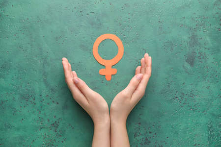 Female hands with symbol of woman on color background. Concept of feminismの写真素材