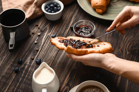 Woman spreading jam onto fresh croissantの写真素材