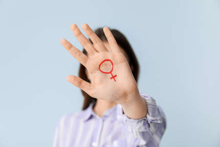 Woman with drawn symbol of woman on her palm against color background. Concept of feminismの写真素材