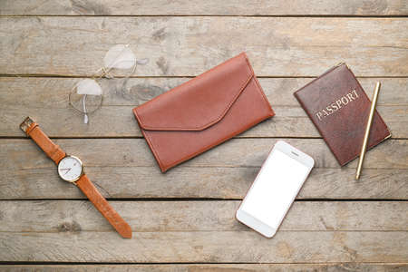 Wallet with mobile phone, passport and accessories on wooden background