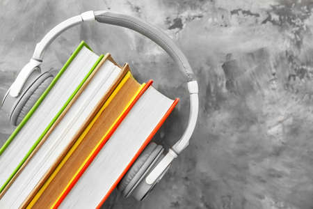 Books and modern headphones on gray background. Concept of audiobookの写真素材